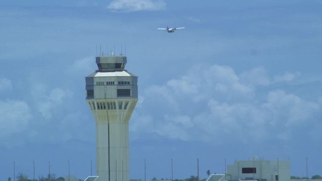Daytime shot of a control tower at airport with plane passing by in slow motion