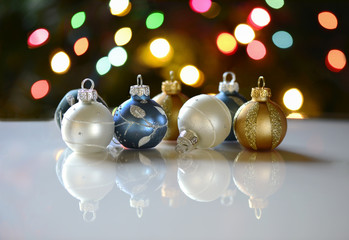 Ornaments and  their reflections in front of Christmas tree lights