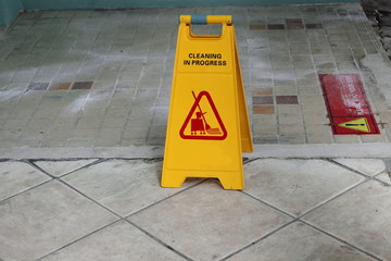 Yellow caution cleaning progress sign on the floor outdoors