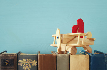 Valentine's day background. Wooden toy plane with heart over old books.