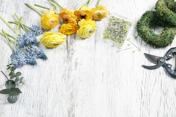 Florist workplace: flowers and accessories on white wooden background