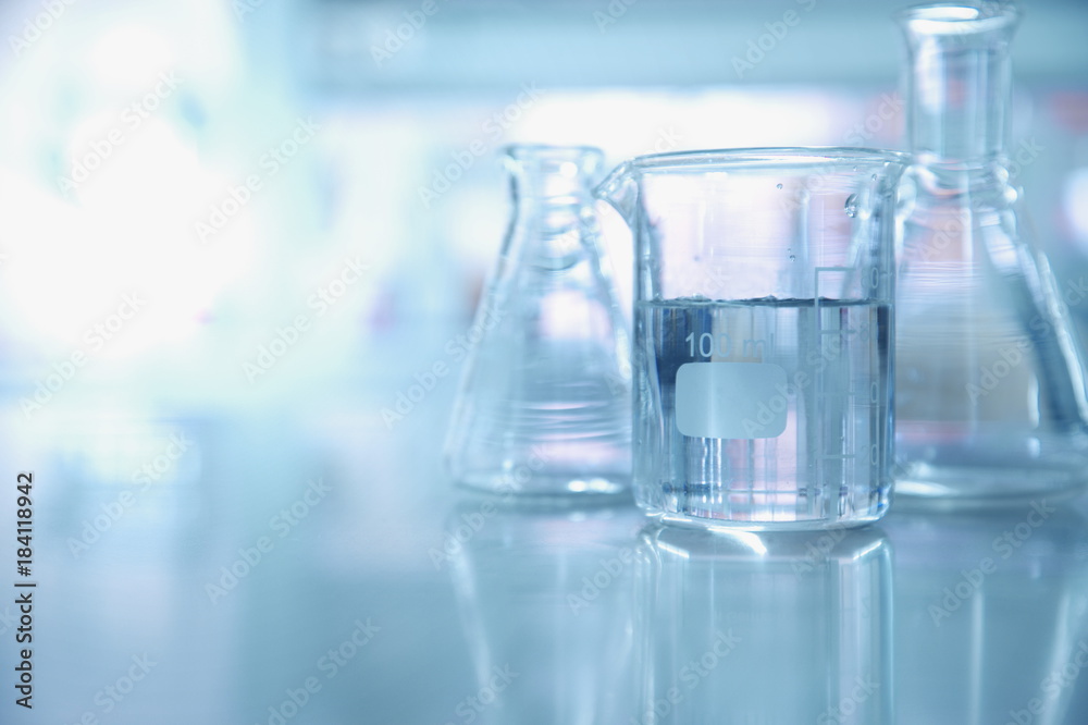 Wall mural experiment water in beaker and flask in chemistry science laboratory background