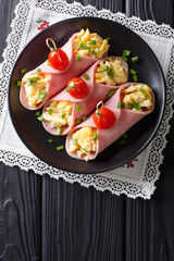 Festive snack: roll ham stuffed with scrambled eggs and tomatoes close-up. Vertical top view