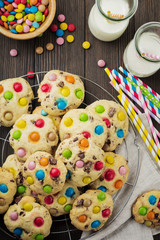 Children's cookies with colorful chocolate sweets in sugar glaze on a brown wooden background. Selective focus. Top view. Place for text.