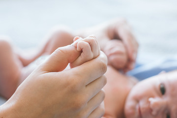cute newborn baby hold mother by the thumb. happy motherhood. family values. © golubovy