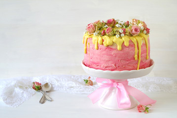 festliche rosa Erdbeer-Buttercreme-Torte mit gelb eingefärbtem Zuckerguss und mit Rosen und Schleierkraut dekoriert