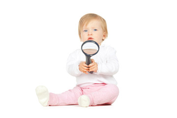 Caucasian baby girl holding magnifying glass isolated on white background
