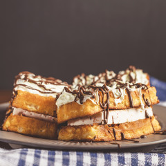 waffles with cream and chocolate on plate on wooden table, free space for text.