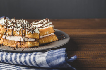 waffles with cream and chocolate on plate on wooden table, free space for text.