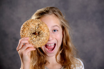 blond girl looking through a big bagel