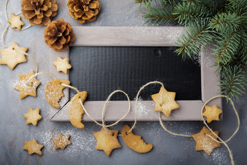 Homemade shortbread star shape sugar with sugar powder and  branch of fit-tree on thread over blue texture surface. Selektive focus.  Christmas or New Year background.  Top view with space.