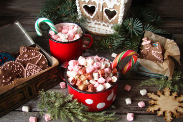 Christmas drink. Red mug of hot coffee with marshmallows, gingerbread house, cookies in a box on wooden background. New Year. A rustic style.
