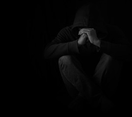 Young man sitting alone in dark room with depressed and anxiety disorder.