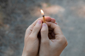 Burning match in hands.