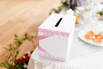White with pink pattern box for gifts on the table of the newlyweds. Planting and tools for newlyweds, a honeymoon box for gift envelopes with money.