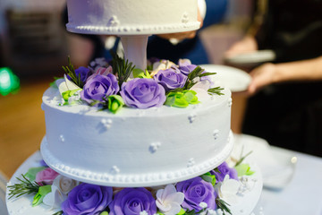 Yogurt white tiered wedding cake decorated with blue roses on the occasion of the wedding day.