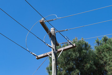 Strommast mit Blickrichtung Himmel und einem Baum im Hintergrund