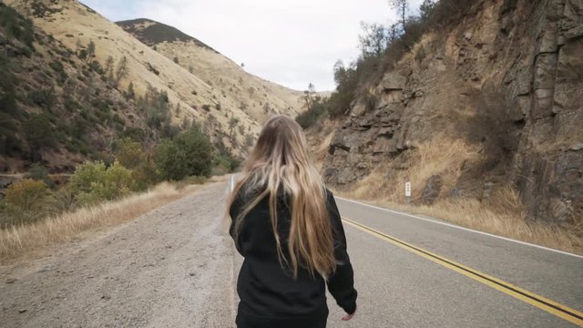 gimbal shot of teen girl walk on road near merced river