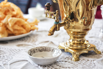 Old samovar and delicious pastry on a table covered with a knitted tablecloth