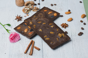 chocolate bar filled with cashew  nuts  lie old wooden table with cracked paint on the surface. rustic style
