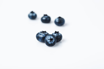 three blueberry berries on white isolated background with shadows and behind very blurred.