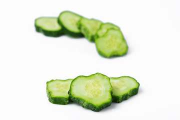 three slices of a cucumber sliced slices on a white isolated background with shadows and behind...