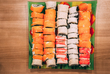 colored sushi made at home lie on a square tray on a wooden surface