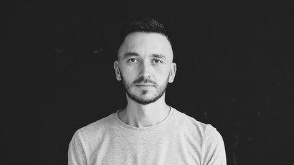 Closeup portrait of young concentrated man looking at camera on black background