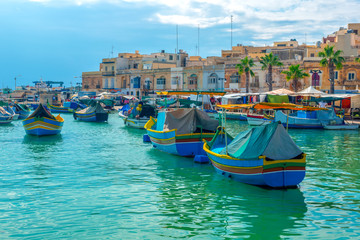 Fototapeta na wymiar beautiful view of european harbor with village Marsaxlokk, market and traditional colorful Luzzu fishing boats, Malta