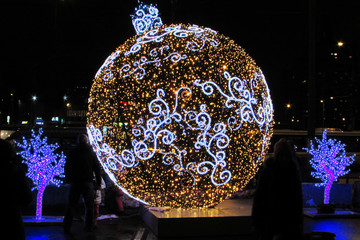 A huge New Year's glowing ball in motley garlands on the city street