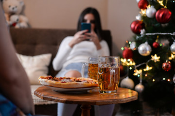 Girls eat pizza and talk in New Year's Night. Girls drink beer and eat pizza in front of Christmas tree