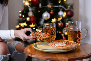 Woman takes a piece of pizza from a plate. Pizza on the table in New Year's Eve. Mixture pizza Italian food.