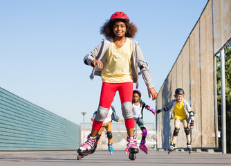 Fototapeta na wymiar African girl rollerblading with friends at stadium