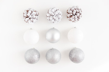 White Christmas background from above. Frosty pine cones, white and silver colored decoration balls. Minimalist style.