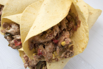 Fajitas consisting of chicken stew with red and green pepper, with red onion, pickled cucumber and spices wrapped in a corn cake.