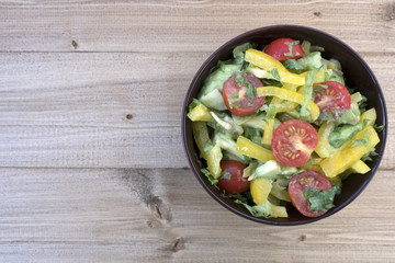 Appetizing vegetable salad consisting of tomatoes, avocado, yellow sweet pepper, lettuce and seasonings.