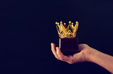 Man's hand holding crown award trophy for show victory or winning first place. Glitter overlay.