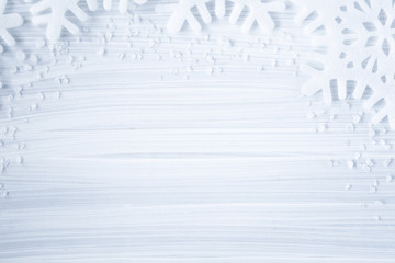 White artificial snowflakes on the cold, frosty wooden background. Mock up for holiday post card and Christmas offers as advertising or other ideas. Winter time concept. Empty place for a text.