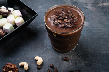 Chocolate smoothie with nuts and marshmallow on dark  background