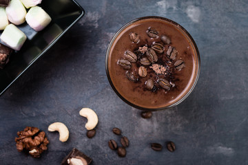 Chocolate smoothie with nuts and marshmallow on dark  background