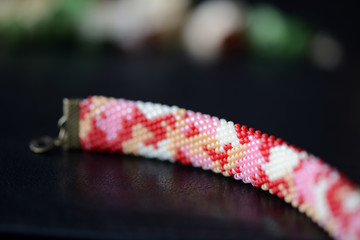 Red camouflage seed beads bracelet on a dark background close up
