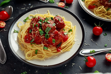Spaghetti pasta meatballs with tomato sauce, basil, herbs parmesan cheese on dark background