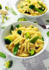 Pasta with green vegetables broccoli, Mange tout and creamy sauce in white plate