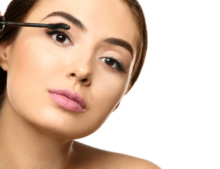 Fototapeta premium Beautiful young woman with eyelash extensions applying mascara, on white background