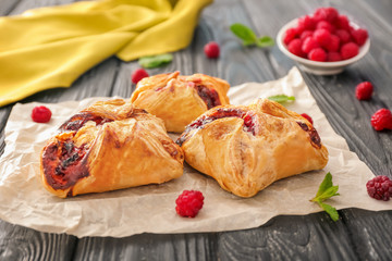 Parchment with delicious puff pastries on wooden table