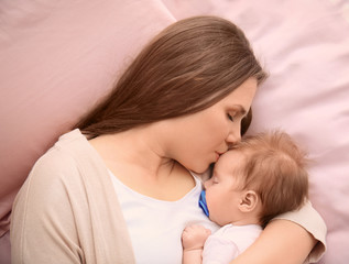 Fototapeta na wymiar Young mother and cute baby sleeping on bed at home