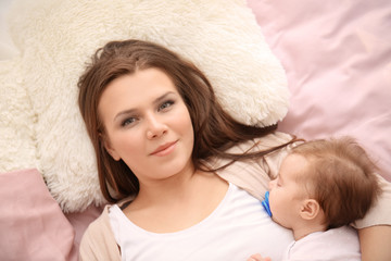 Young mother and cute baby sleeping on bed at home