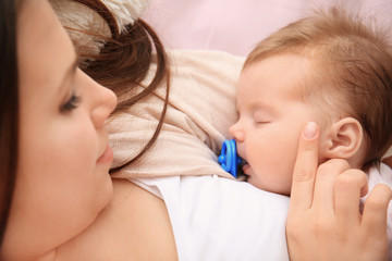 Young mother and sleeping baby on bed at home