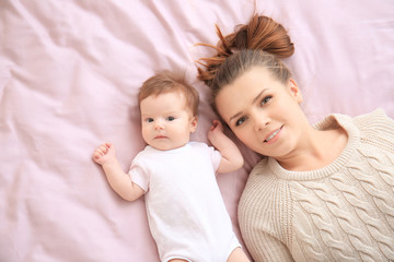 Young mother and cute baby on bed at home