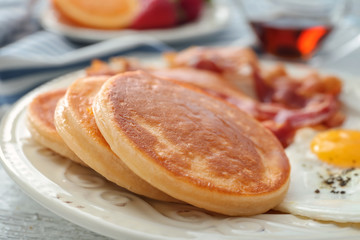 Plate with yummy pancakes, fried bacon and egg on table, closeup